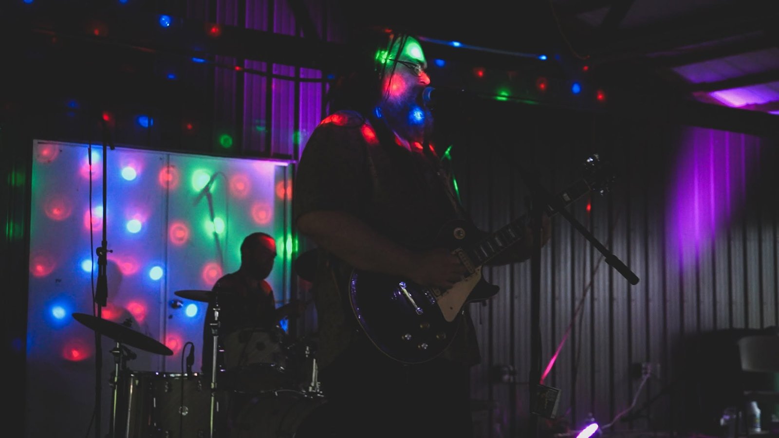 Robert Nellinger singing and playing guitar under stage lights